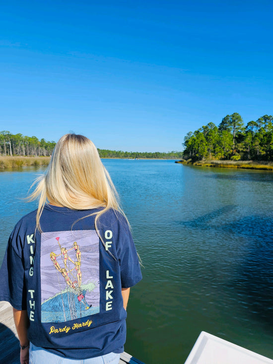 Girl standing on the lake looking out at the view. She is wearing our King of the Lake T-shirt.